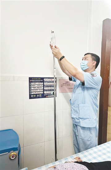 吴益浩核对药液、为患者调整输液流速。