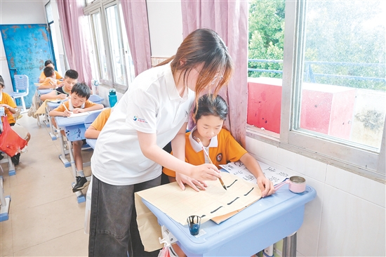 社会实践队队员指导学生练习硬笔、软笔书法。