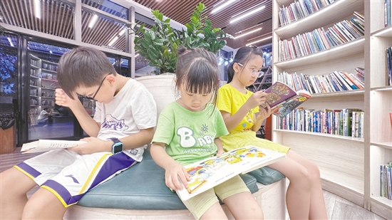 低年级学生围坐在书架旁阅读绘本。