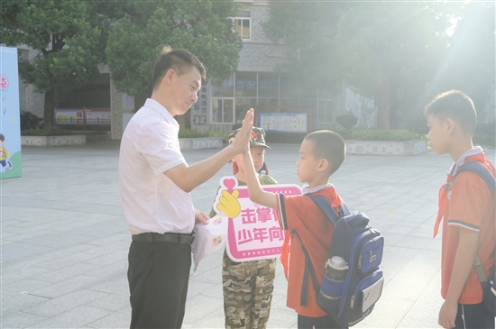 紫茶小学党委书记谭国池与学生逐一击掌。 紫茶小学党委书记谭国池与学生逐一击掌。
