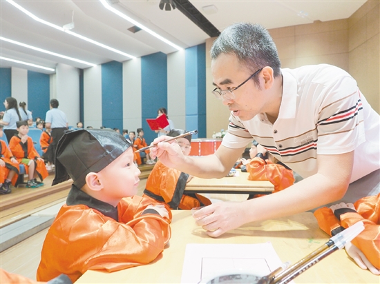 在朱砂启智环节,教师用毛笔在新生的额头点上红痣。 在朱砂启智环节,教师用毛笔在新生的额头点上红痣。