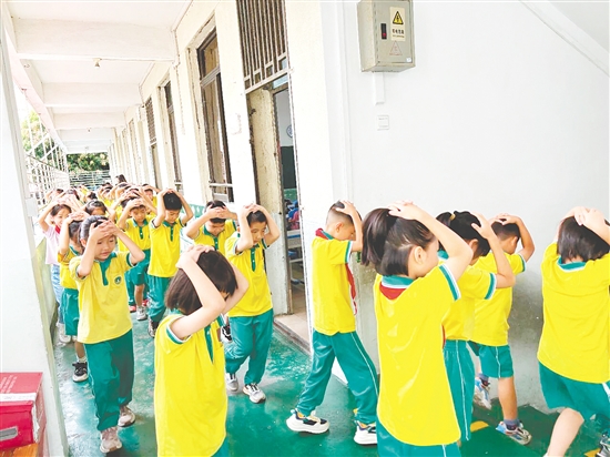 演练中,学生双手抱头、紧贴墙角,按照指定的逃生路线快速有序地撤离至操场安全区域。 演练中,学生双手抱头、紧贴墙角,按照指定的逃生路线快速有序地撤离至操场安全区域。