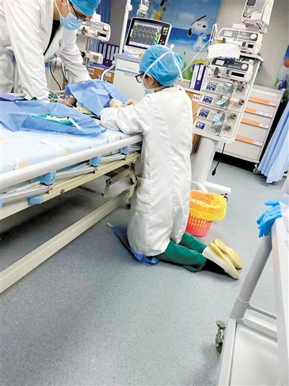 为了操作更加平稳，该院PICU主治医师刘琴跪在病床旁为患儿进行穿刺检查。
