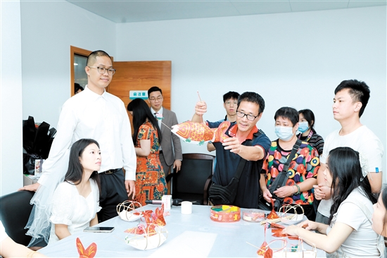 昨日，在新会区民政局婚姻登记处，工作人员向刚领证的新人们展示新会鱼灯制作技巧。