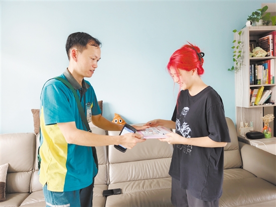 梁悦敏从邮政投递员手中接过清华大学录取通知书。
