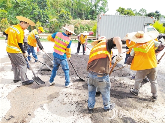 公路养护人员在烈日下修补新中公路上的坑洼路面。