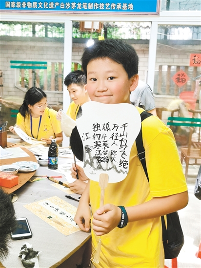 美国华裔青少年李恩诚用茅龙笔在扇面上写下唐诗。