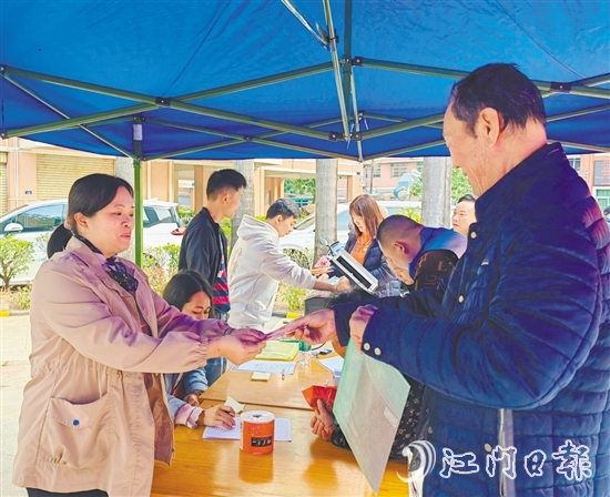 业委会工作人员向业主派发现金福利。