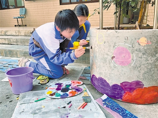 学生们在校园内的花墩上进行精心绘制，为校园风景增色添彩。