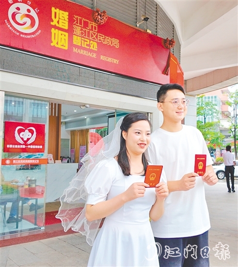 一对新人在蓬江区民政局婚姻登记处门口合影留念。