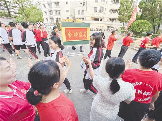 台山一中在送考路上设置了“金榜题名”大字帖，教师身穿红衣与学生击掌，为学生加油。
