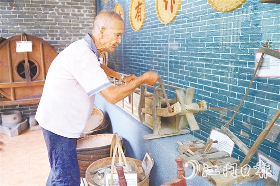 新华村打造农耕文化展馆，留住乡村记忆。图为村中老人向记者介绍农具。