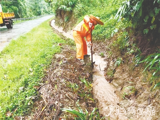 道路养护人员清理被泥沙落叶堵塞的边沟涵洞，确保雨水快速排走。