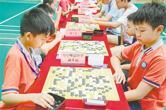 小棋手目不转睛盯着棋盘，沉浸于黑白棋子的博弈中。