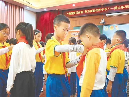 活动中,老队员熟练地为新队员系上红领巾。 活动中,老队员熟练地为新队员系上红领巾。