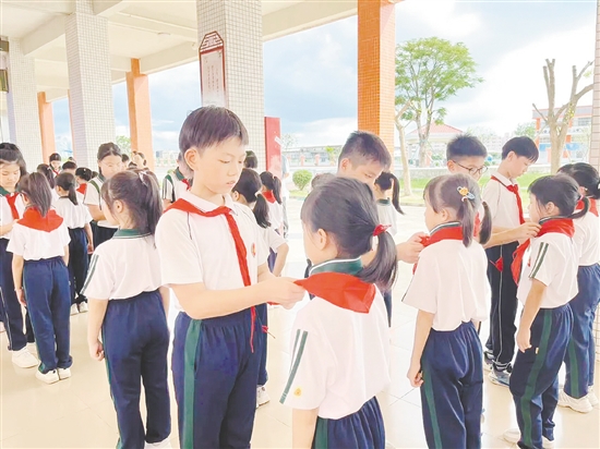 仪式上，老队员为新队员戴上鲜艳的红领巾。