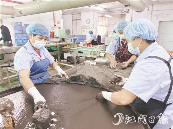 工作人员将裹稻草灰浆的咸蛋放到干稻草灰滚动一下，就完成咸蛋包裹工艺。