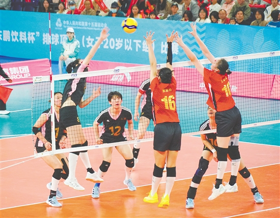 山东队（红衣）球员腾空而起，奋力封堵上海队的强力进攻。