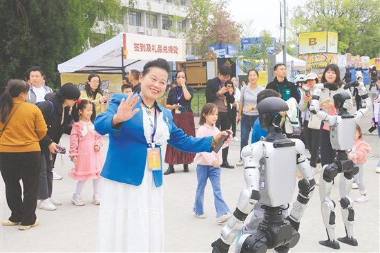 在“乐业五邑”创业创新大赛现场，华文媒体记者代表与人形机器人互动。
