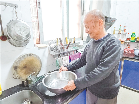 榕树村村民麦成建在厨房用干净的自来水清洗餐具。