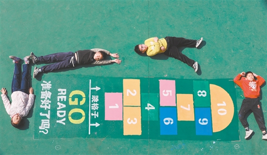 画完“跳格子”后，学生们兴奋地躺在地上合影。