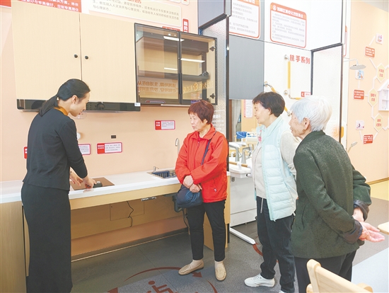 工作人员(左一)向长者介绍适老化厨房燃气灶,其具有防干烧和自动熄火功能。 工作人员(左一)向长者介绍适老化厨房燃气灶,其具有防干烧和自动熄火功能。