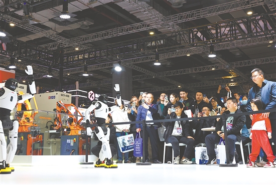 图为当日，参观者在展会现场观看人形机器人舞蹈表演。新华社发