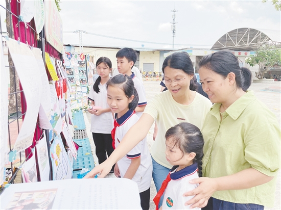 老师、学生与家长一起欣赏以书香为主题创作的手抄报。