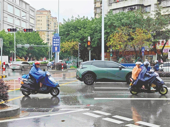 昨日，新会下起阵雨，市民纷纷穿上雨衣。