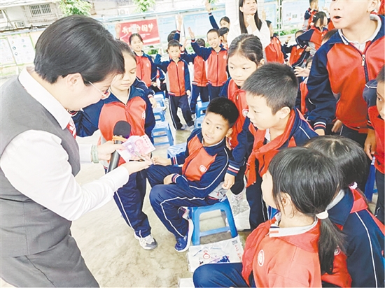宣讲员以第五套人民币为教具，让孩子们学会识假技巧。
