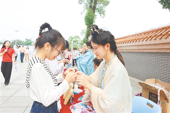 在汉服社摊位，学生现场体验制作缠花、琉璃饰品。