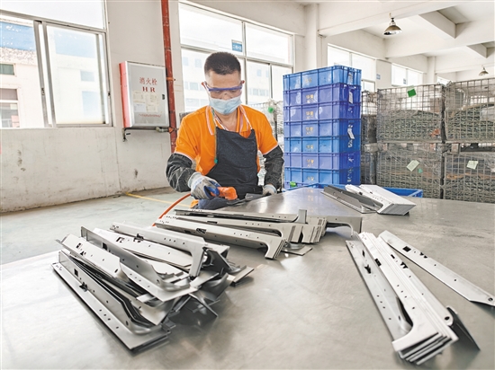 在江门市华誉制造有限公司的生产车间，52岁的残疾人员工黄日道在认真打磨零部件。