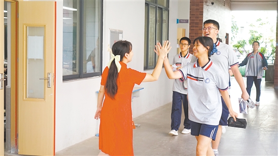 “考完啦！”江门市华侨中学学生们与老师击掌庆祝。