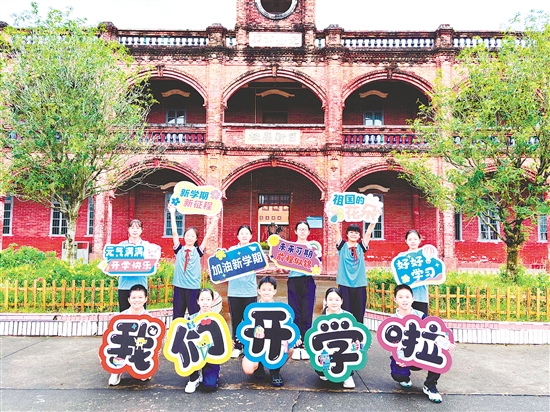 台山市李星衢纪念学校的学生们手举“我们开学啦”创意标语牌，在百年红楼前定格美好瞬间，满怀朝气奔赴新学期。