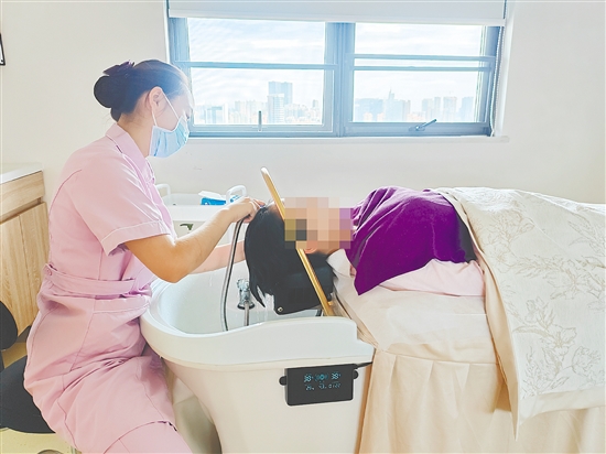 护理人员用中药为产妇洗头。