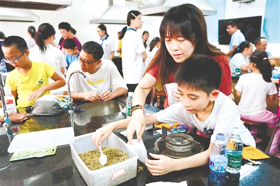 家长和孩子一起制作中草药香囊。