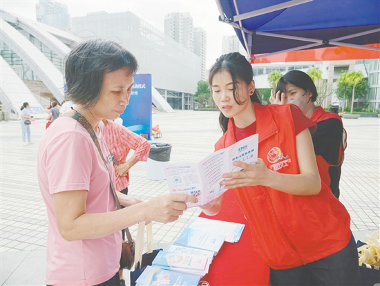 工作人员向市民介绍参保流程。 工作人员向市民介绍参保流程。